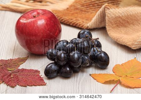 Apple, Grapes, Checkered Plaid And Dry Leaves On Wooden Boards. An Autumn Still Llife.