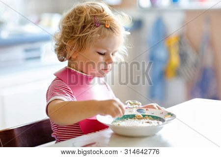 Adorable Baby Girl Eating From Spoon Vegetable Noodle Soup. Food, Child, Feeding And Development Con