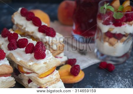 Dessert Milfey. Strips Of Puff Pastry With Curd Cream Raspberry Berries And Peach Slices. In The Bac
