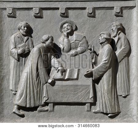 ZURICH, SWITZERLAND - JUNE 23, 2018: Luther and Zwingli dispute about the Lord's Supper at Marburg, relief on the door of the Grossmunster (