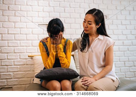 Asian Mother Comforting Crying Teenage Daughter In Miserable, Stressed, Depressed, Sad State Of Mind