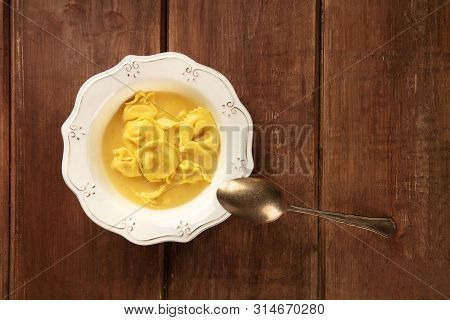Tortellini Served With Broth, Shot From The Top On A Dark Rustic Wooden Background