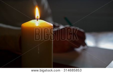 Caucasian Man Writing A Letter  On Pine Wood Table, Shallow Depth Of Field, Focu On The Candle Light