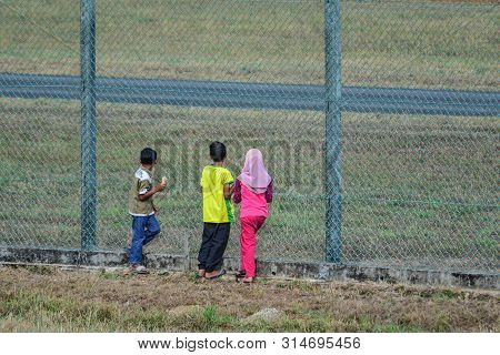 Langkawi, Malaysia - Mar 30, 2019. Children Looking Through The Iron Fence Of Langkawi Airport (lgk)