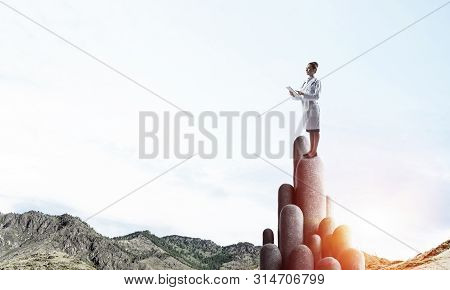 Young Female Doctor With Folder In Hands Satnding On Stone Column