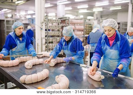Butchers Processing Sausages At The Meat Factory.