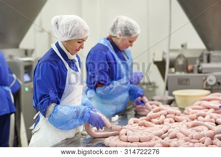 Butchers Processing Sausages At A Meat Factory.