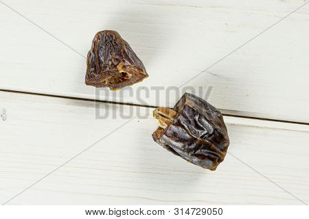Group Of Two Halves Of Dried Brown Date Medjool Flatlay On White Wood