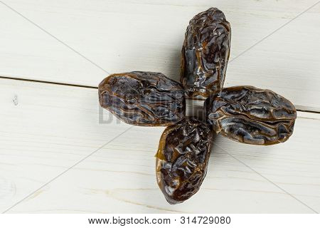 Group Of Four Whole Dried Brown Date Medjool Flatlay On White Wood
