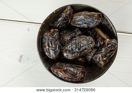 Lot Of Whole Dried Brown Date Medjool On Grey Ceramic Plate Flatlay On White Wood