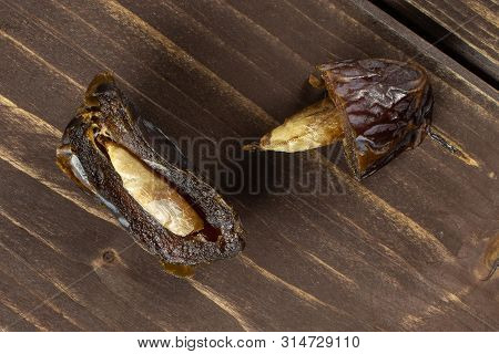 Group Of Two Halves Of Dried Brown Date Medjool Flatlay On Brown Wood