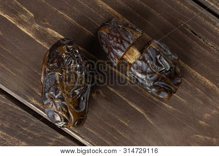 Group Of One Whole Two Halves Of Dried Brown Date Medjool Flatlay On Brown Wood