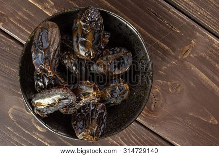 Lot Of Whole Dried Brown Date Medjool On Grey Ceramic Plate Flatlay On Brown Wood