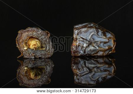 Group Of Two Halves Of Dried Brown Date Medjool Isolated On Black Glass