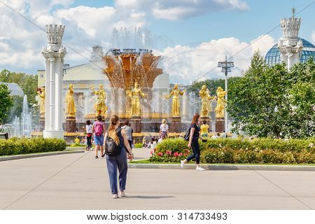 Moscow, Russia - July 22, 2019: Tourists Walking Against Friendship Of Peoples Fountain In Vdnh Park