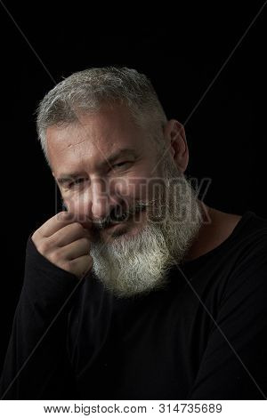 Portrait Of A Smiling Brutal Gray-haired Man With A Gray-haired Lush Beard On A Black Background, Se