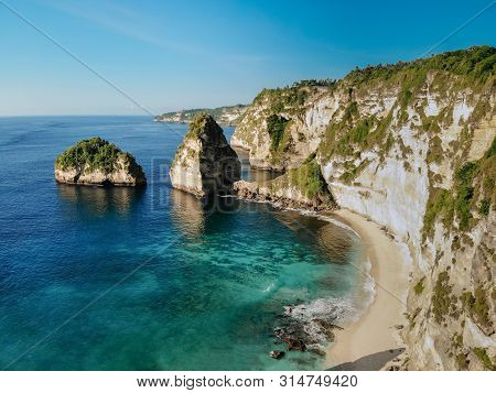 Aerial Drone View Of Tropical Beach, Sea Rocks And Turquoise Ocean, Blue Sky. Atuh Beach, Nusa Penid