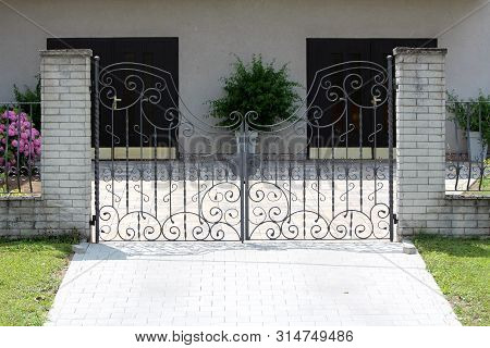 Large Wrought Iron Family House Driveway Entrance Doors Mounted On Two Stone Tiles Covered Concrete 