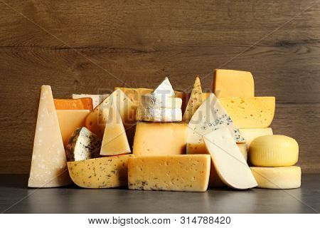 Different Types Of Delicious Cheese On Table Against Wooden Background