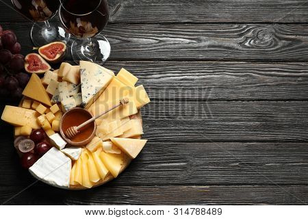 Different Types Of Delicious Cheese Served On Black Wooden Table, Top View. Space For Text
