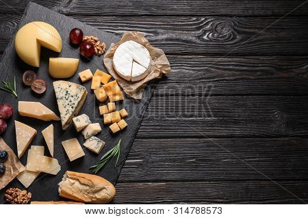 Different Types Of Delicious Cheese Served On Black Wooden Table, Top View. Space For Text