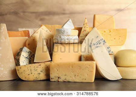 Different Types Of Delicious Cheese On Table Against Wooden Background