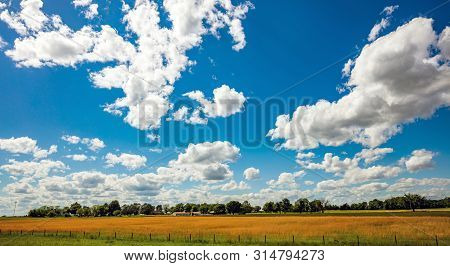Sunny Spring Day In American Countryside. Rural Scene, Farmland With Trees And Buildings, Blue Sky W