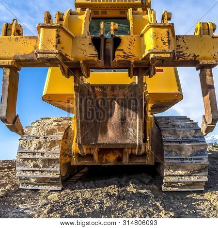 Square Heavy Duty Construction Vehicle With Peeling Yellow Paint And Dirty Metal Tracks