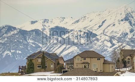 Panorama Frame Winter View Of A Neighborhood On A Hill Against Mountain And An Overcast Sky