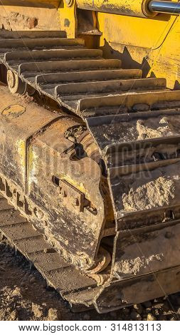 Vertical Dirty Metal Track Pad Of A Yellow Construction Machinery On A Sunny Day.