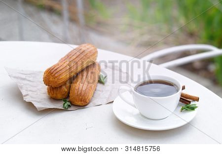 Fragrant Coffee With Eclairs In The Summer Cafe.