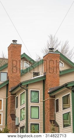 Vertical Frame Homes With White Wall Sidings And Red Brick Chimneys Against Cloudy Sky