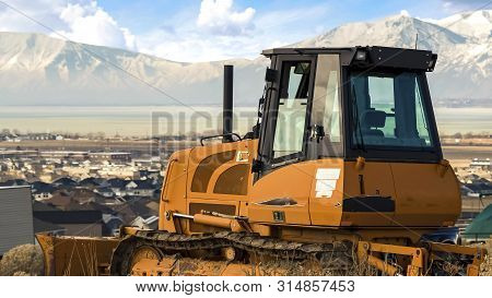 Panorama Frame Yellow Loader On A Hill Overlooking Houses On A Residential Area In The Valley