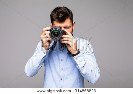 Young Man Take Photo With Dslr Camera Looking At Camera Isolated Over Gray Abackground.