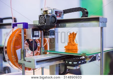 Automatic 3d Printer Machine Printing Plastic Model Of Orange Toy Dragon At Modern Technology Exhibi