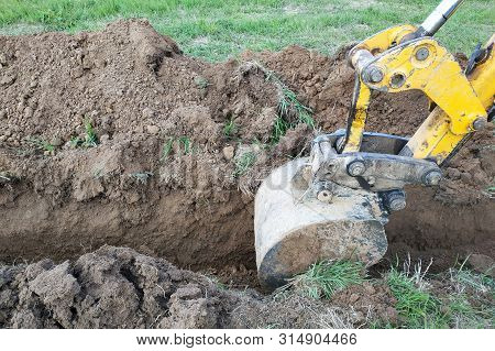 Construction Excavator Digging A Shallow Groove For Electrical Wiring Or Cable.