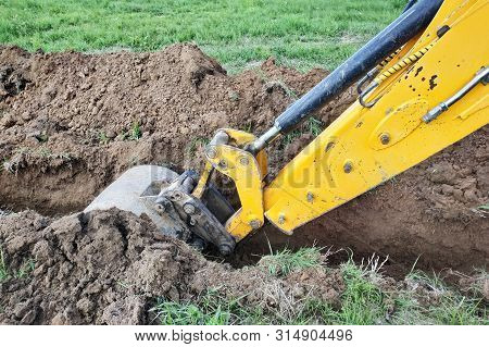 Construction Excavator Digging A Shallow Groove For Electrical Wiring Or Cable.