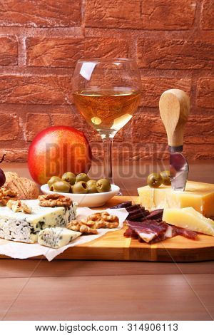 Assortment Of Cheese With Fruits, Grapes, Nuts And Cheese Knife On A Wooden Serving Tray.