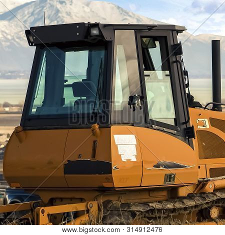 Square Yellow Loader On A Hill Overlooking Houses On A Residential Area In The Valley