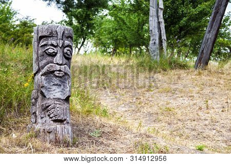 Wooden Idol Of Slavic God By A Path In The Forest. Forest In The Background.
