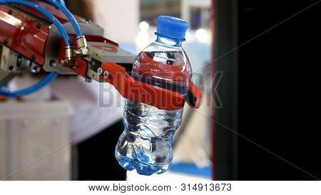 Close Up For The Red Robot Hand Holding A Bottle Of Wate On Blurred Background, Artificial Intellige