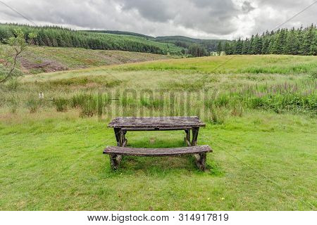 Isolated Park Bench In Wales Countryside, With A View Of A Stormy Sky