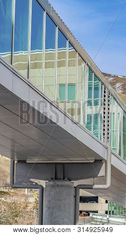 Vertical Skybridge Connected To A Modern Building With Mountain And Blue Sky Background