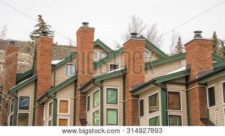 Panorama Homes With White Wall Sidings And Red Brick Chimneys Against Cloudy Sky