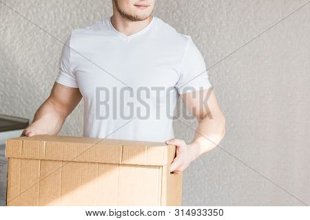 Delivery Strong, Muscular Man Loading Cardboard Boxes For Moving To An Apartment. Professional Worke