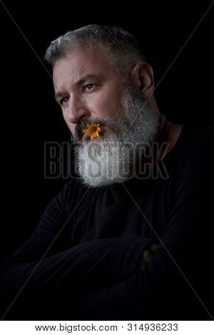 Portrait Of A Brutal Gray Haired Man With A Beard With A Sly Expression On His Face And A Yellow Flo