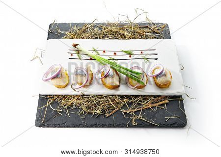Herring Canape with Potato and Onion on Natural Rustic Background. Beautiful Creative Sea Food Design of Fish Fillet with Scallions on Dry Hay and Black Slate