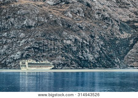 Cruise ship sailing at Glacier Bay, Alaska, on blue arctic sea waters and icebergs. travel background luxury holiday destination.