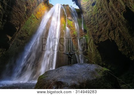 Traveler Stunned By Gljufrabui Waterfall Cascade In Iceland. Location: Gljufrabui Waterfall, Part Of