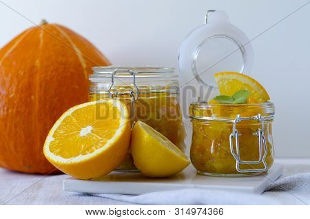 Pumpkin Jam Or Marmalade With Orange And Lemon. In The Background Is A Pumpkin. Two Glass Jars Of Pu